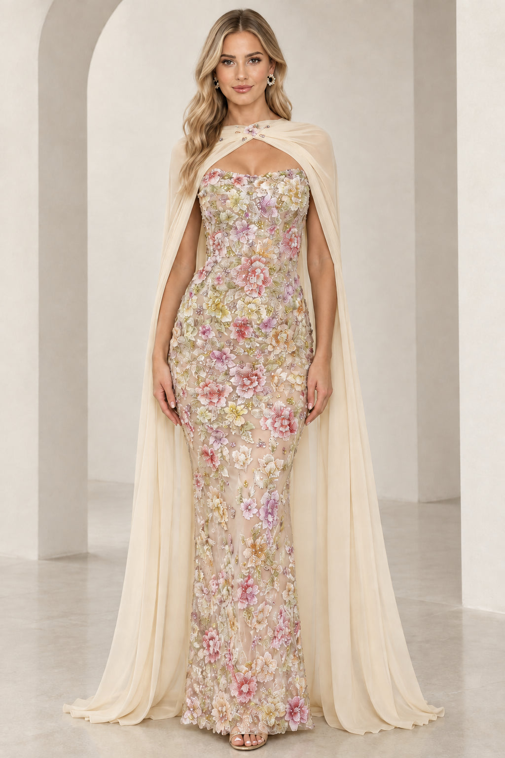Model wearing champagne ivory floral embroidered formal dress with delicate sheer cape