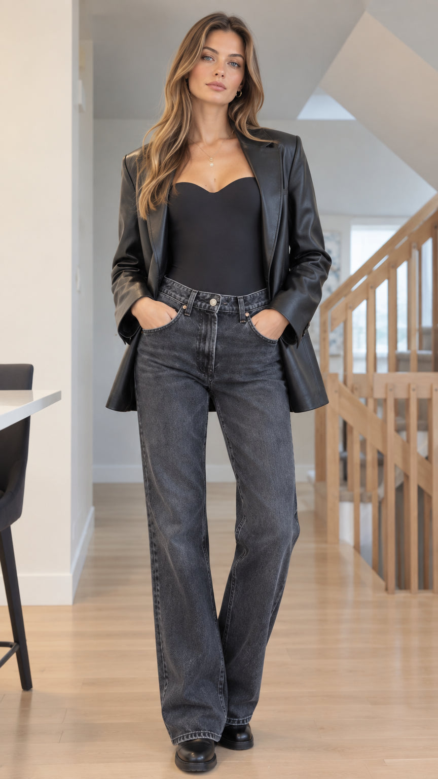 Front full-length view of woman wearing Black tailored faux leather blazer with sweetheart top and grey wide-leg jeans