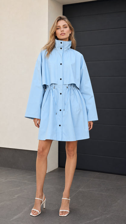 Front full-length view of woman wearing light blue high collar drawstring parka jacket