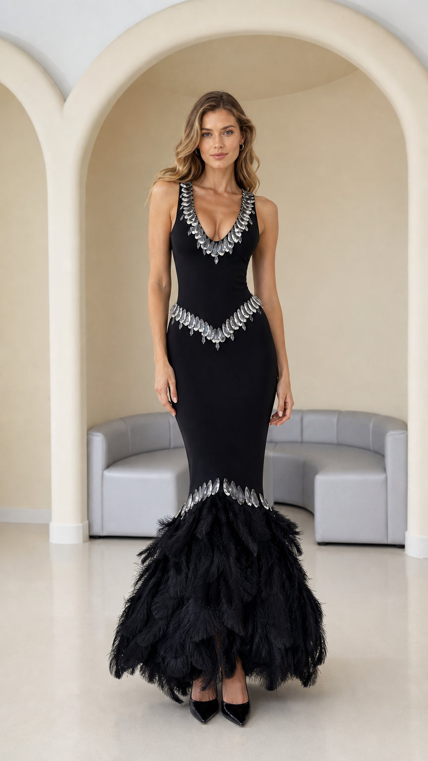 Front view of black sleeveless mermaid evening gown with rhinestone trim and feather hem