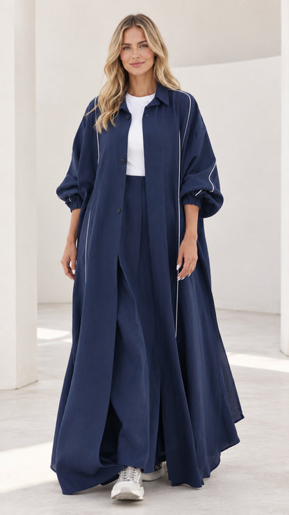 Front full view of woman wearing navy blue maxi duster and matching wide leg pants set with white contrast piping