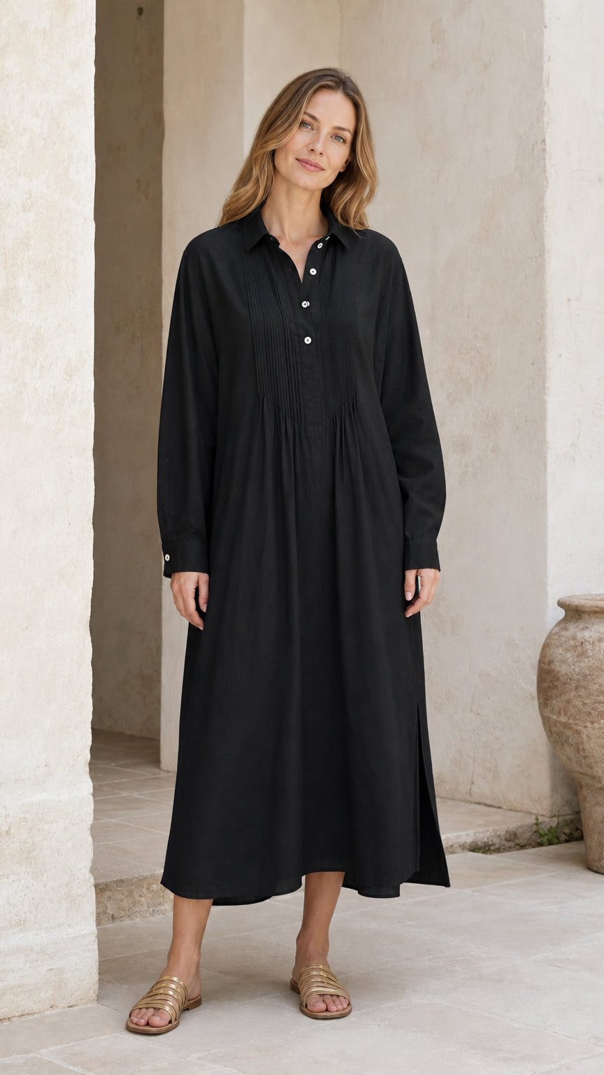 Front full view of woman wearing black long sleeve pleated midi shirt dress