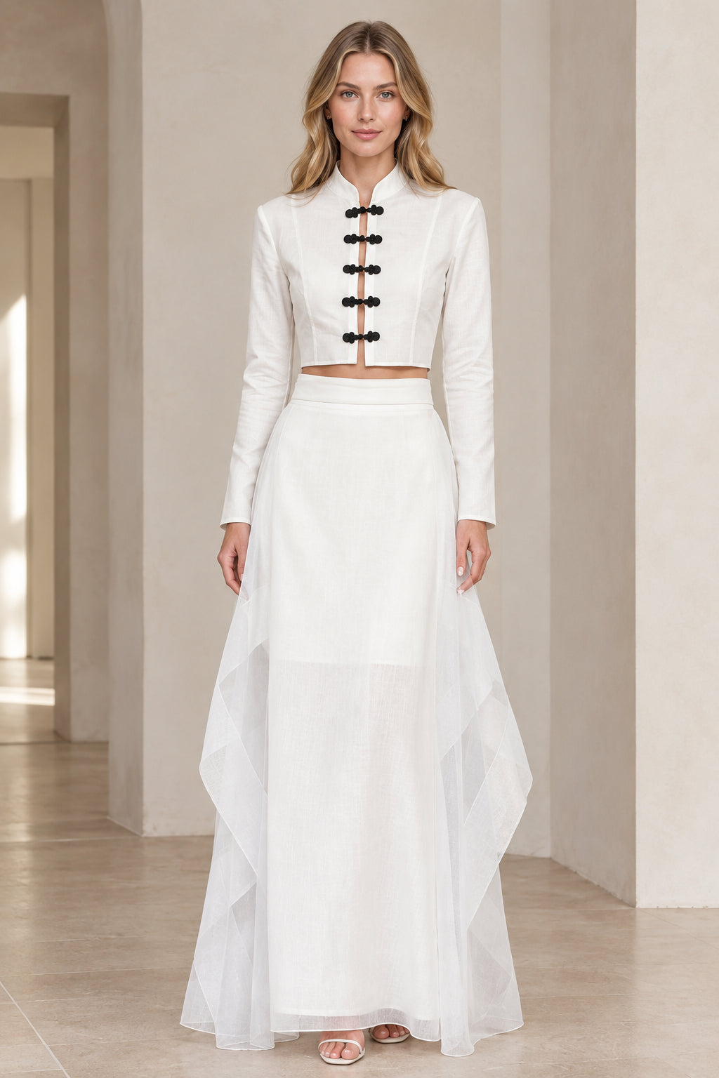 Front view of model wearing white mandarin collar frog button crop top and tiered maxi skirt set