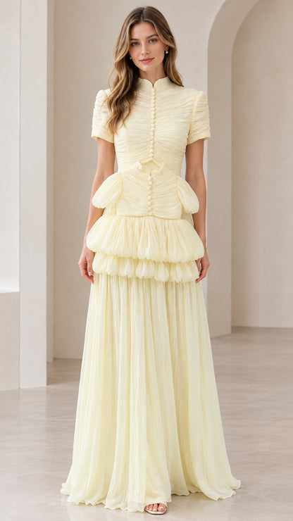 Front view of model wearing pale yellow mock neck tiered pleated maxi dress