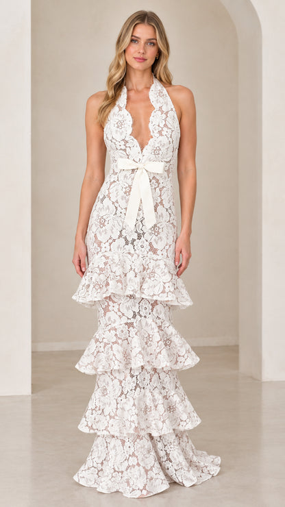 Front view of model wearing White halter neck tiered floral lace maxi dress with waist bow