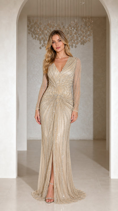 Front full-length view of model wearing champagne embellished long sleeve evening gown with front slit