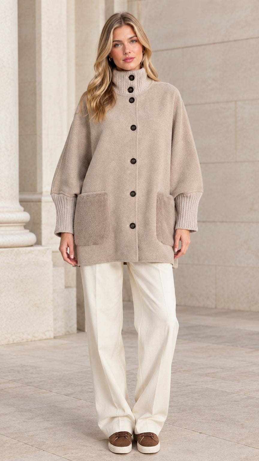 Full front view of a woman wearing a beige relaxed button-down mock neck jacket with wide trousers