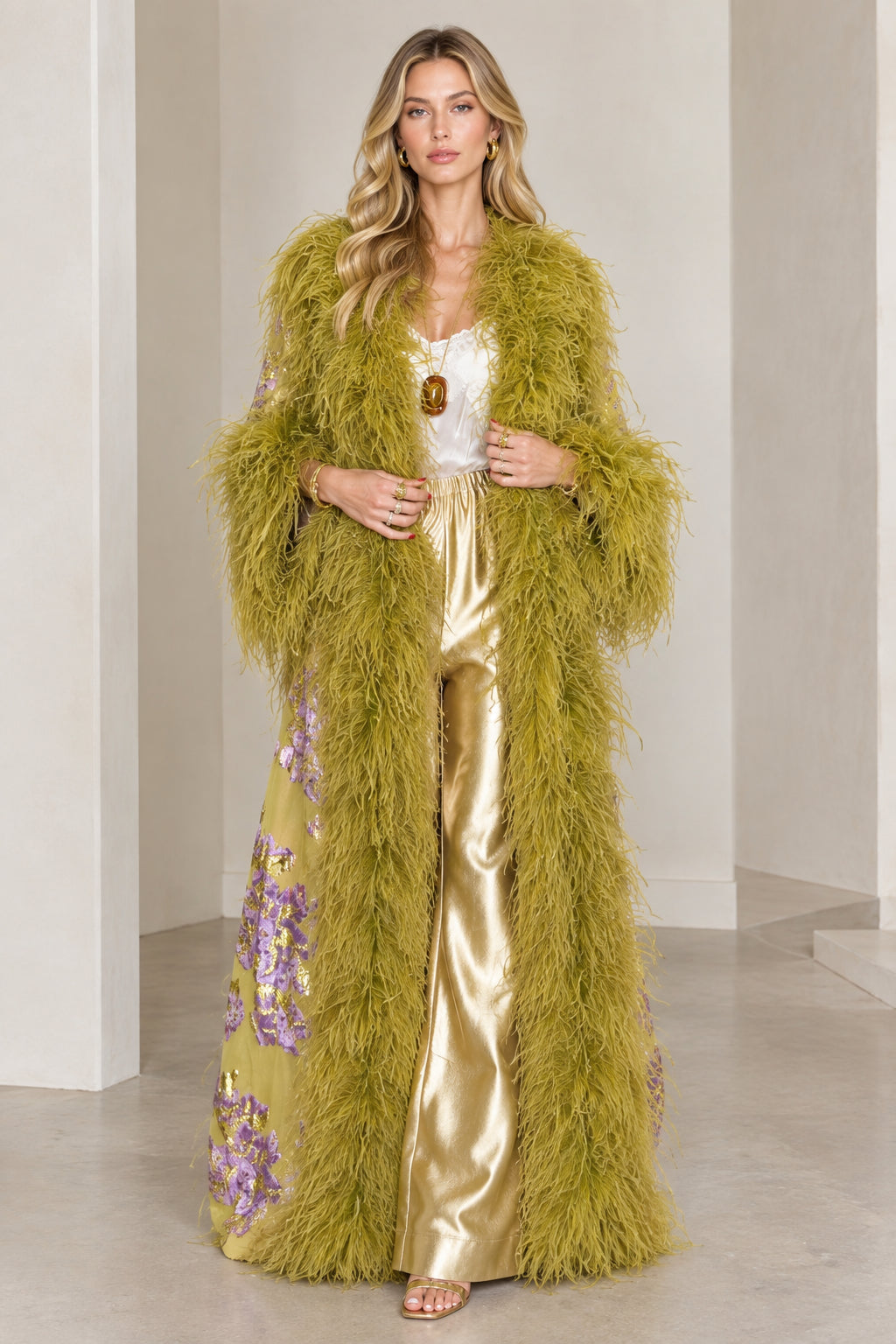 Front full-length view of model wearing olive green floral brocade maxi duster with plush feather trim