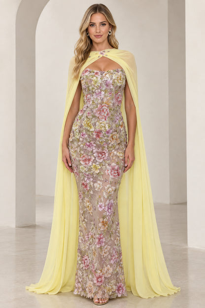 Front view of model wearing yellow floral embroidered strapless evening gown with matching sheer cape