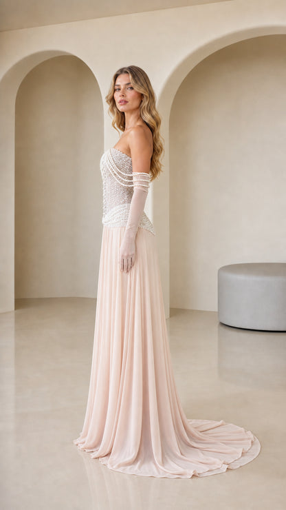 Side profile view of Blush Pink pearl embellished gown showing sweeping train and sheer gloves