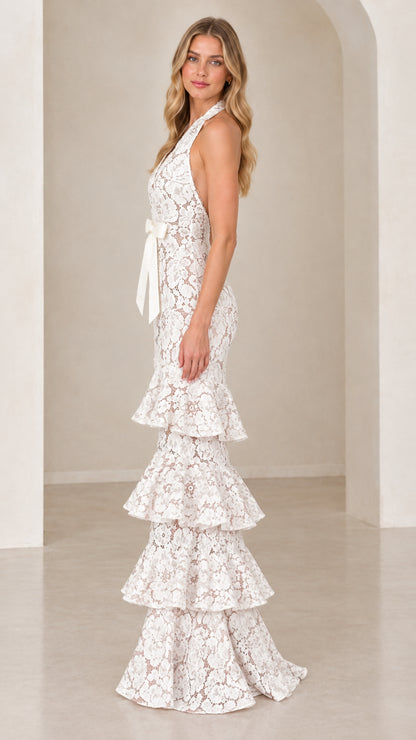 Side profile of model wearing White halter floral lace gown with tiered ruffle skirt