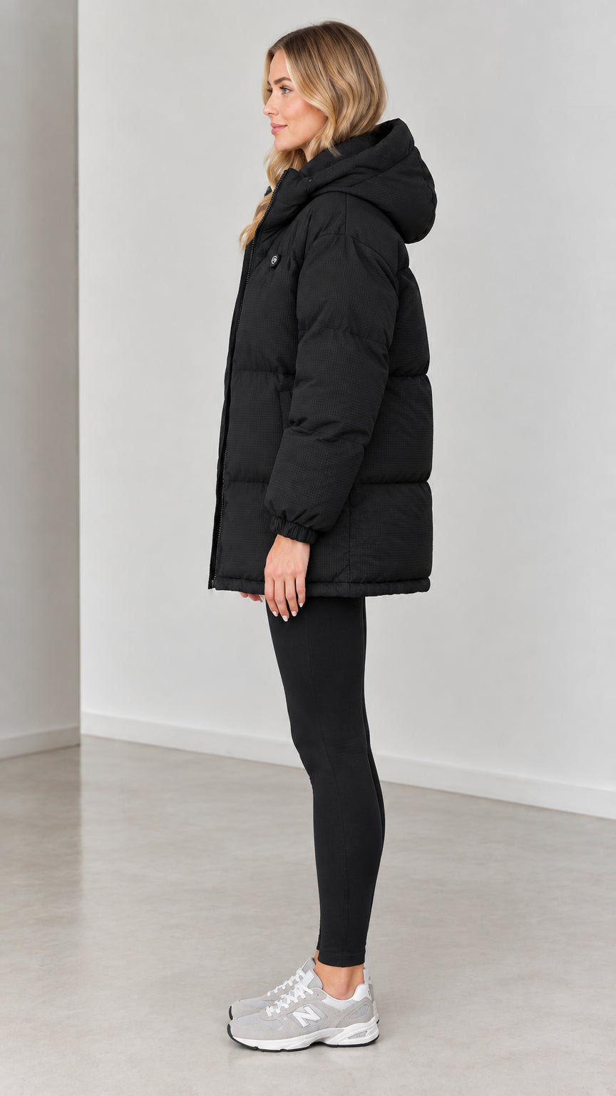 Side profile view of woman wearing black quilted puffer coat with hood