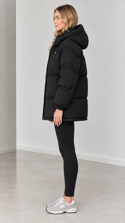 Side profile view of woman wearing black quilted puffer coat with hood