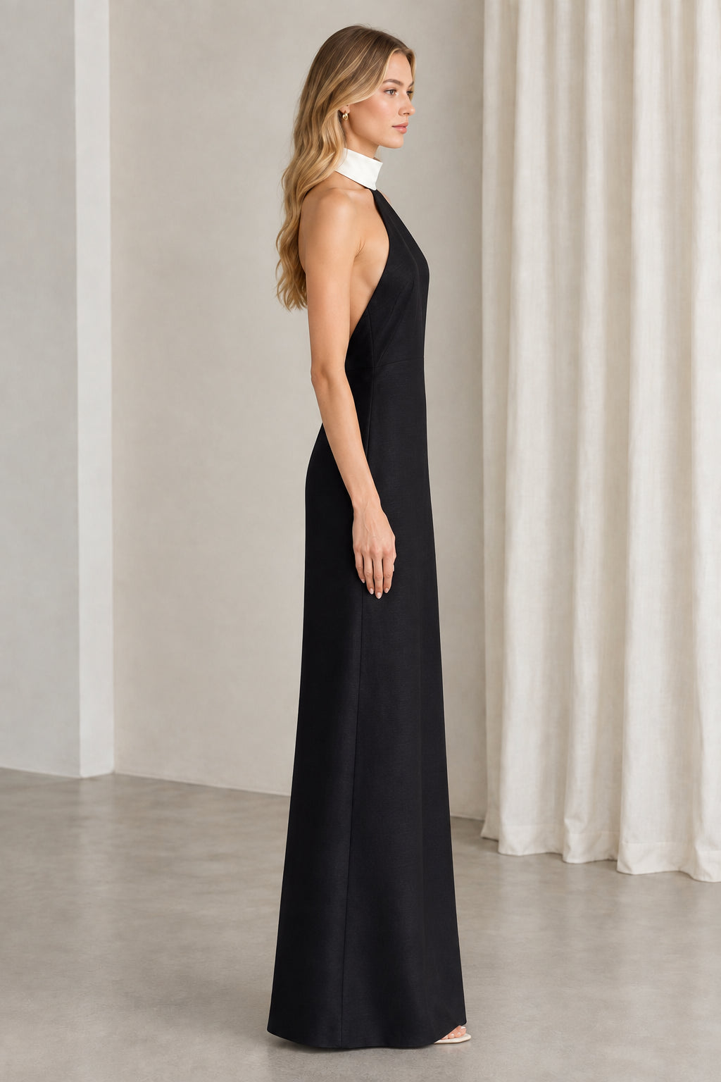 Side profile of woman wearing black open-back halter evening dress