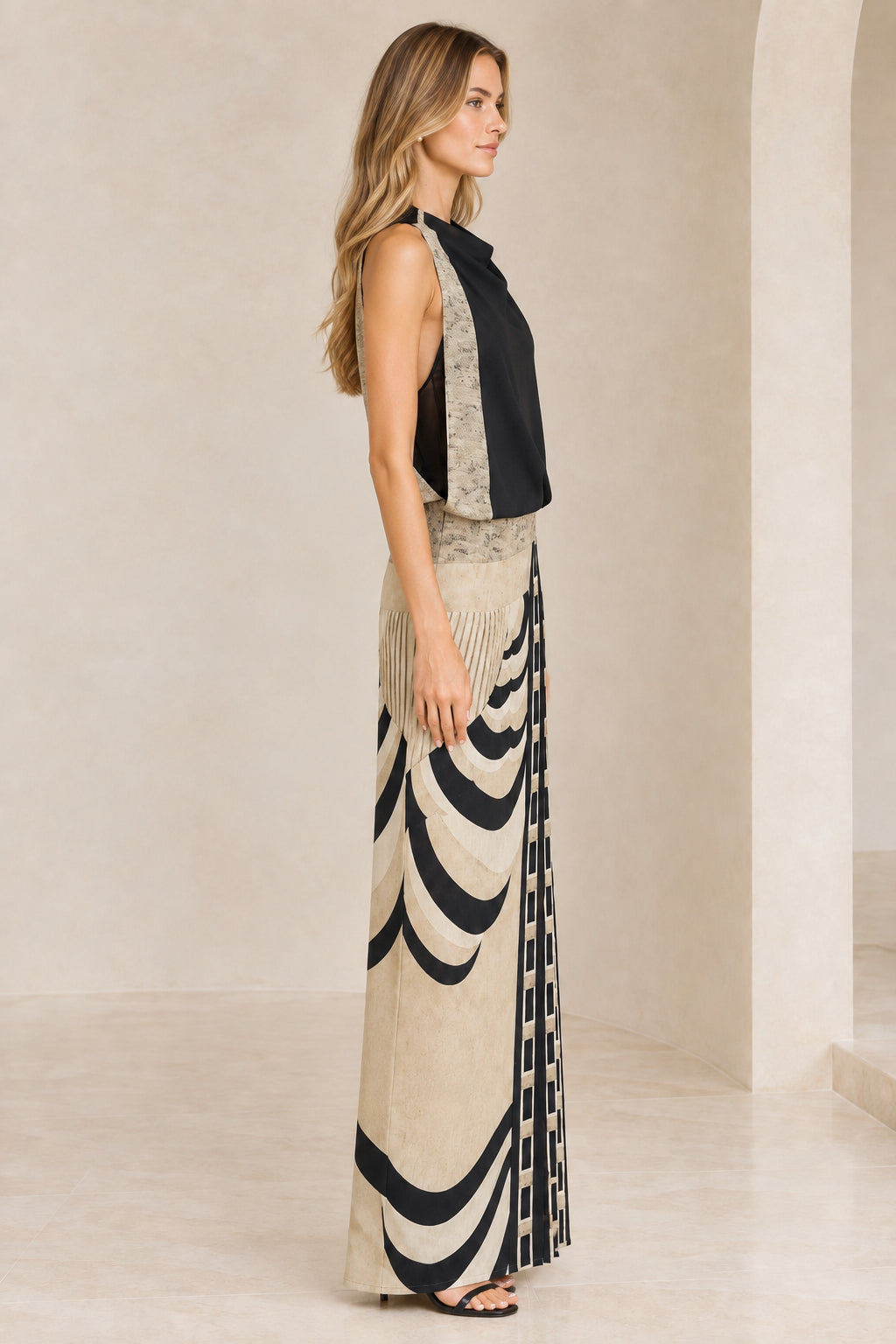 Side profile of model wearing black sleeveless geometric maxi dress