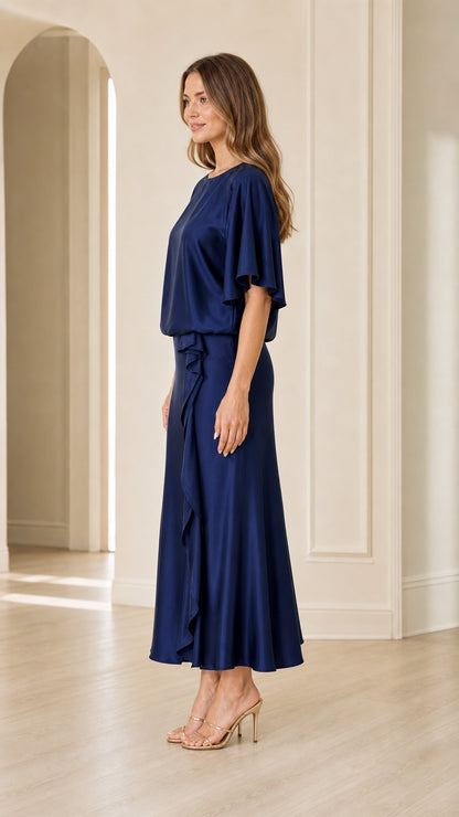 Side profile of woman in navy blue flutter sleeve satin evening maxi dress