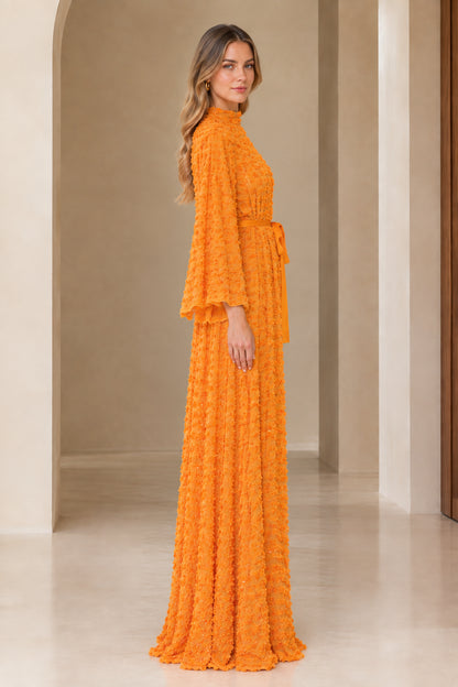 Side full view of orange textured sequin evening maxi gown with belt