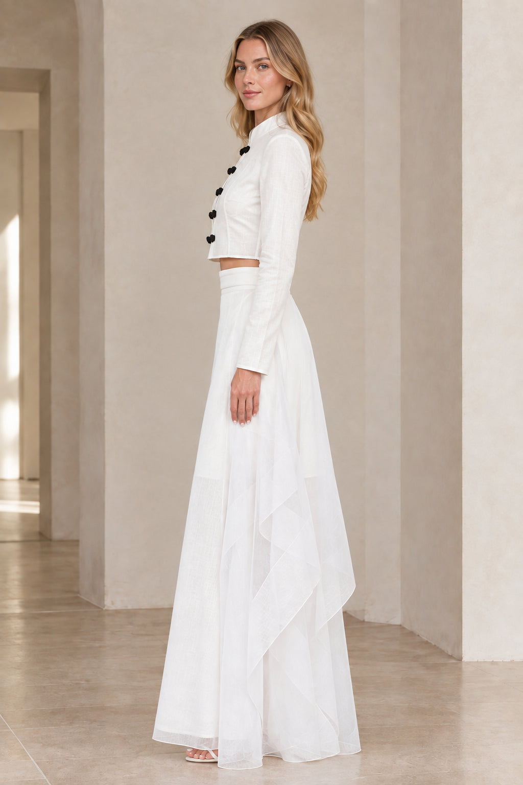 Side view of model wearing white two-piece crop top and draped maxi skirt set