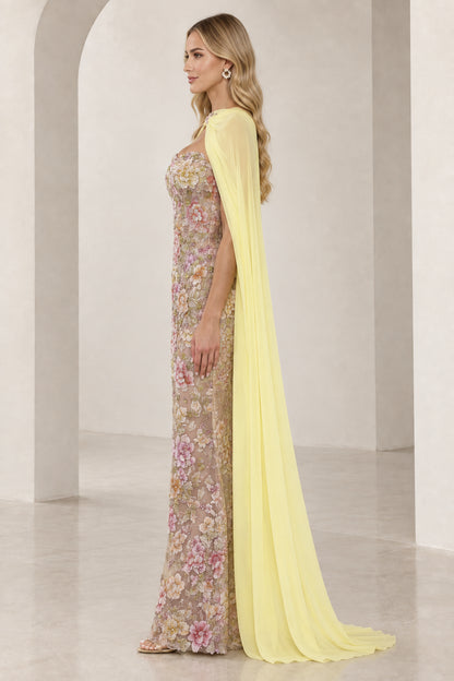 Side profile of model wearing floral embroidered column gown with flowing yellow chiffon cape