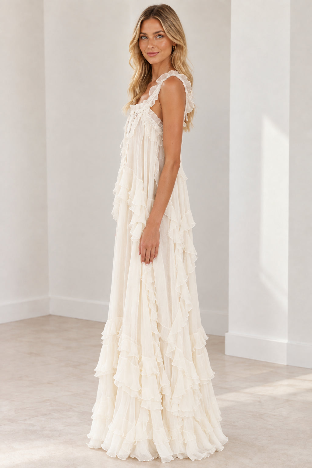 Side angle of model wearing cream sleeveless tiered ruffle maxi dress