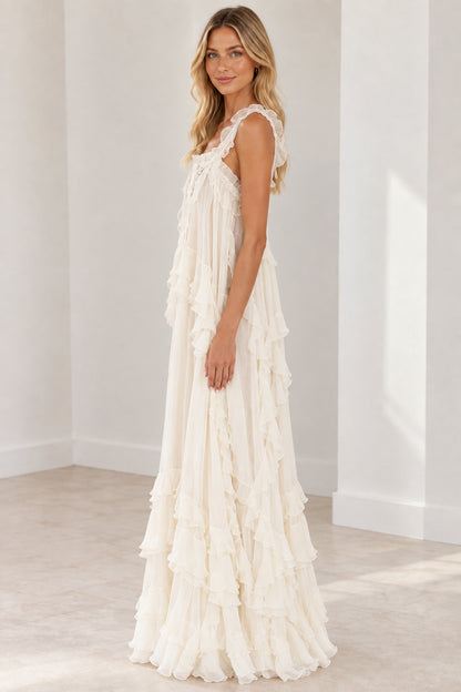 Side angle of model wearing cream sleeveless tiered ruffle maxi dress