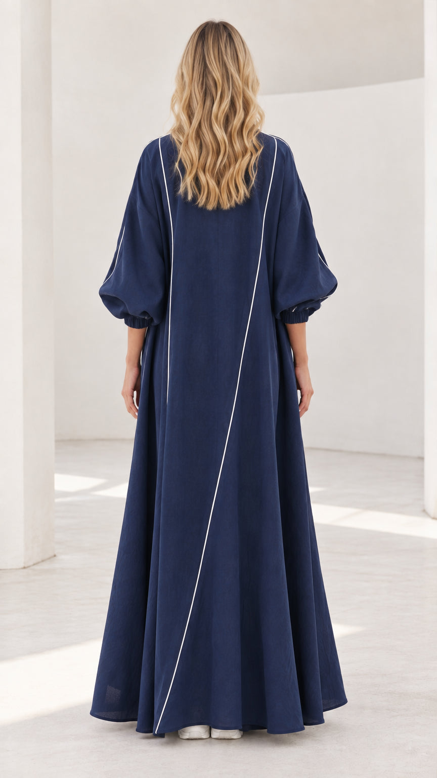 Back view of navy maxi duster showing diagonal white piping detail and flowing drape