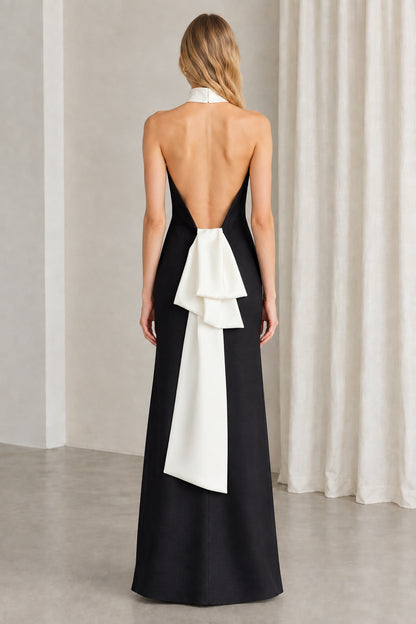 Back view of black halter gown showcasing open back and draped white bow