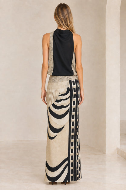 Back view of model wearing black cowl neck maxi dress with printed column skirt