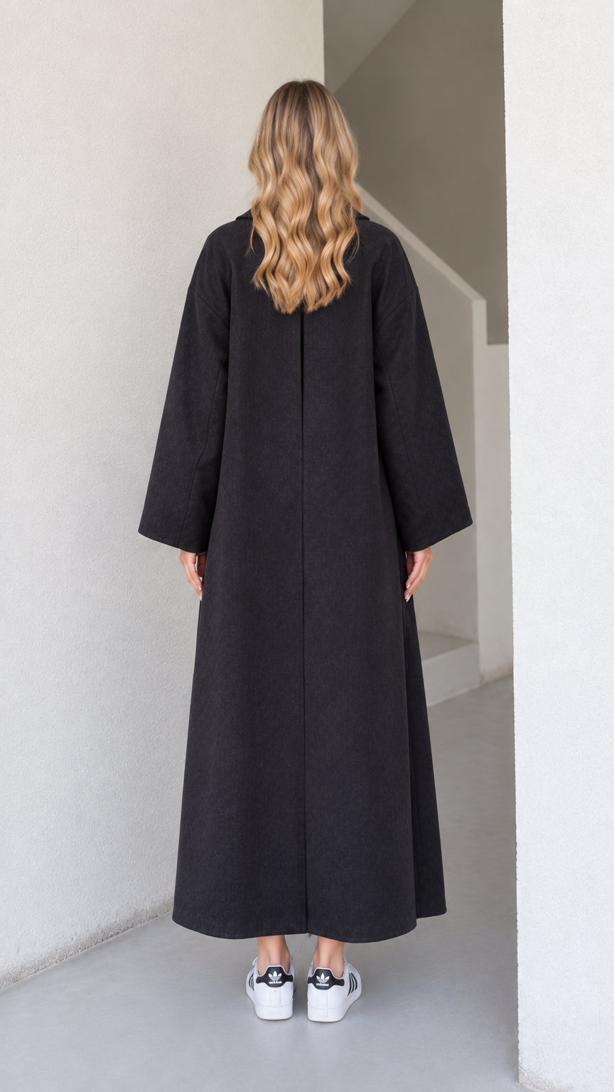 Back view of the black maxi overcoat featuring a back inverted pleat detail