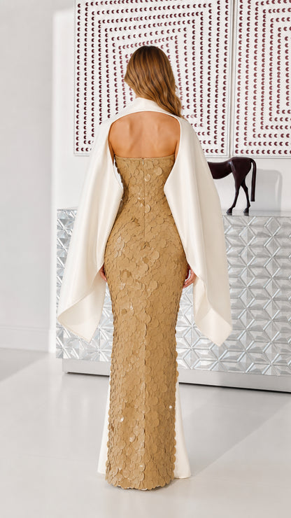 Back view of gold sequin maxi dress showcasing open back and draped cape