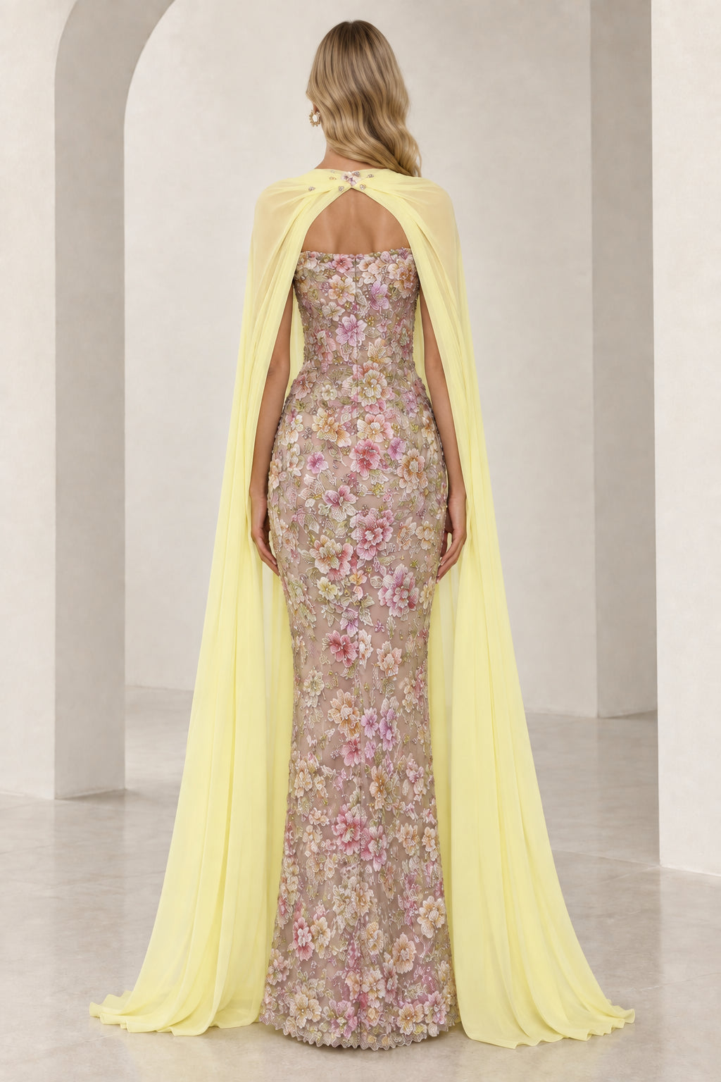 Back view of model showcasing full-length yellow chiffon cape and strapless embroidered dress