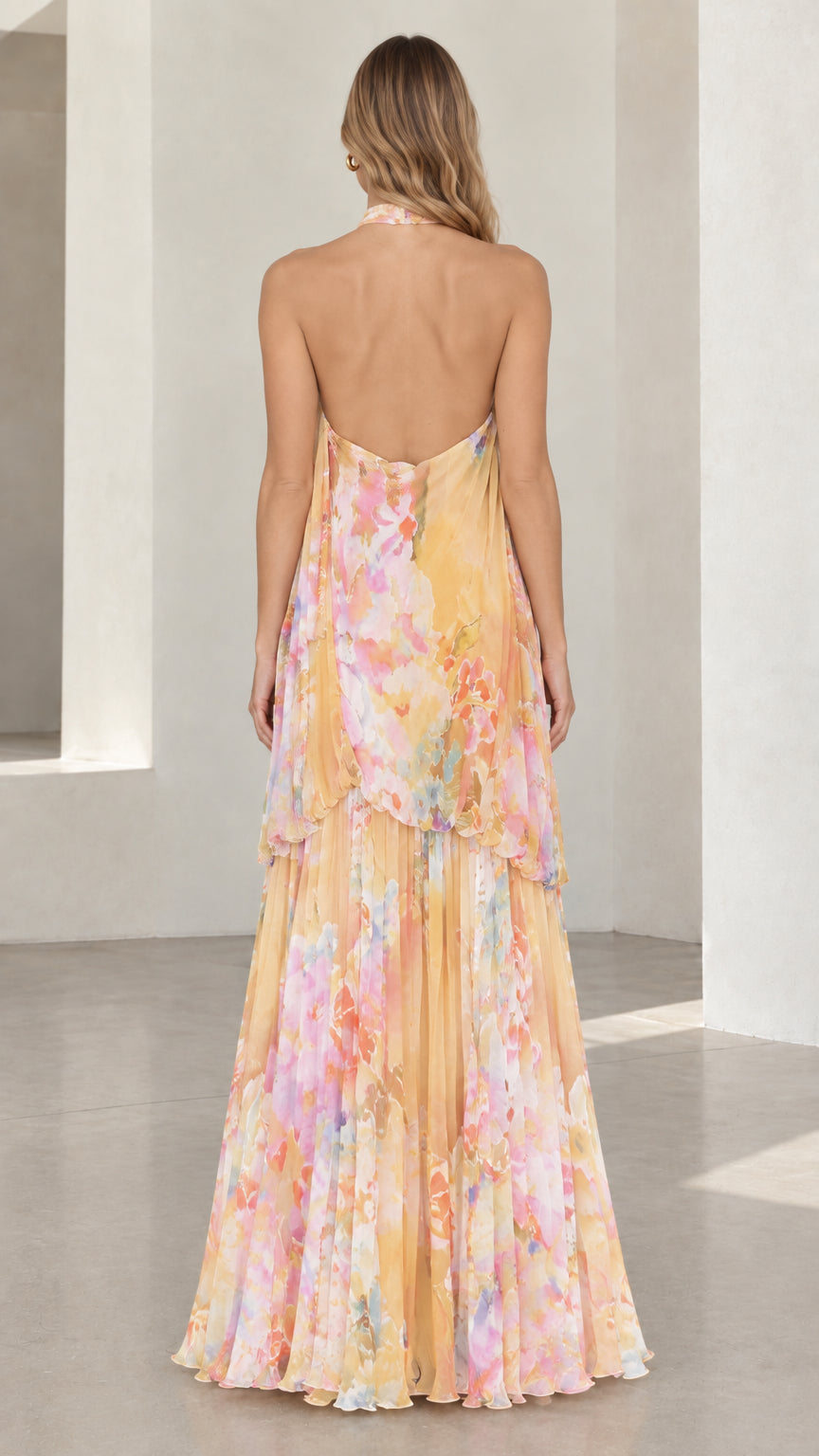 Back view of model showing open back design of yellow floral halter dress