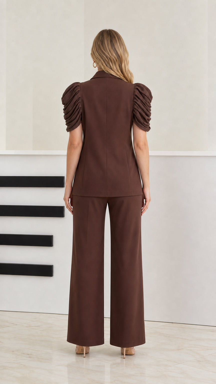 Back view of model wearing brown short puff sleeve suit jacket and straight trousers