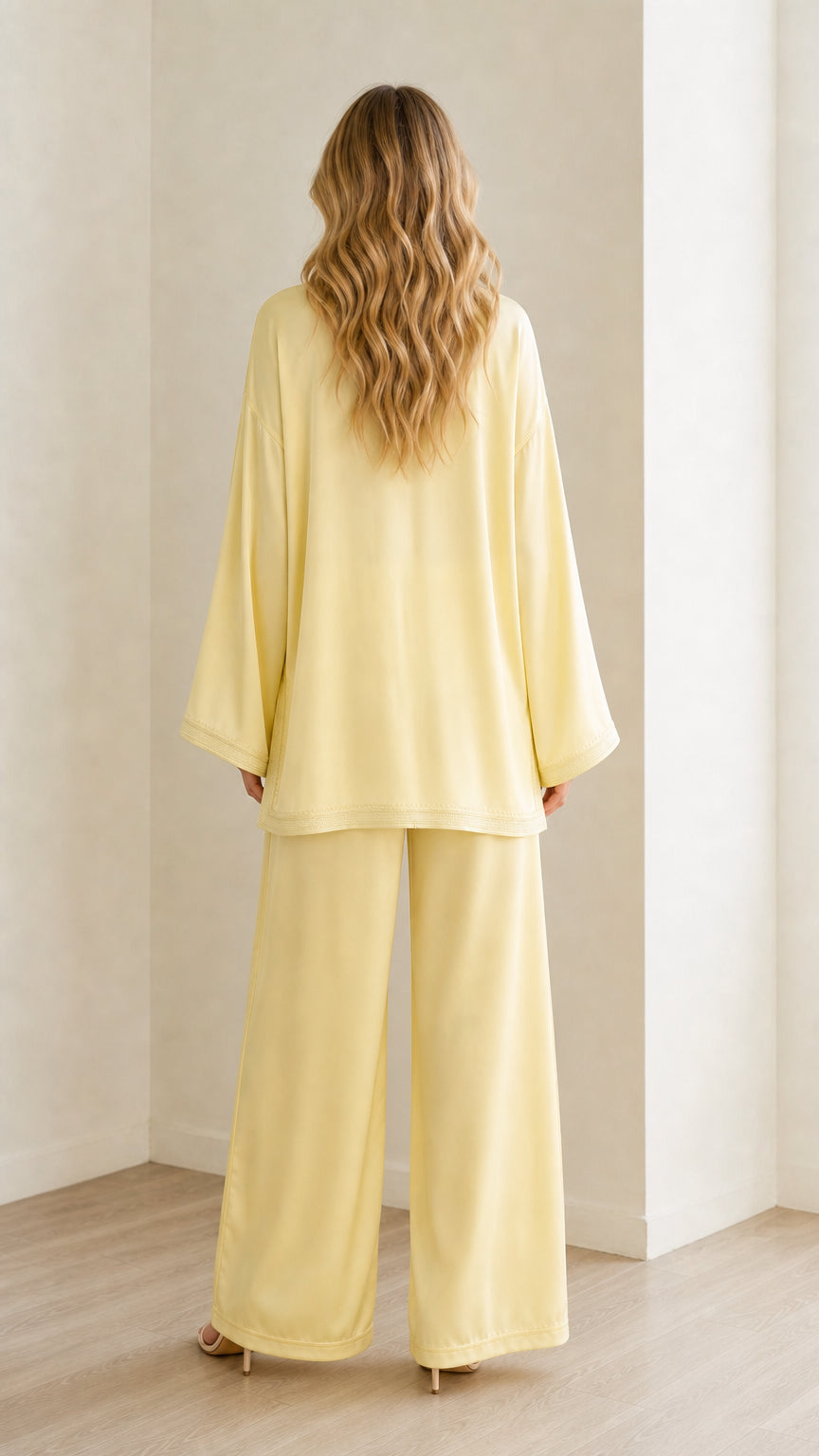 Back view of woman wearing pastel yellow long sleeve tunic top and matching palazzo pants