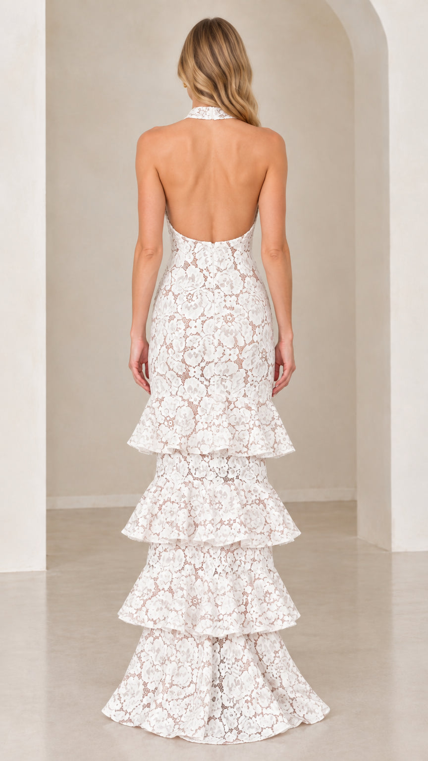 Back view of model showing open back design on White tiered lace evening gown