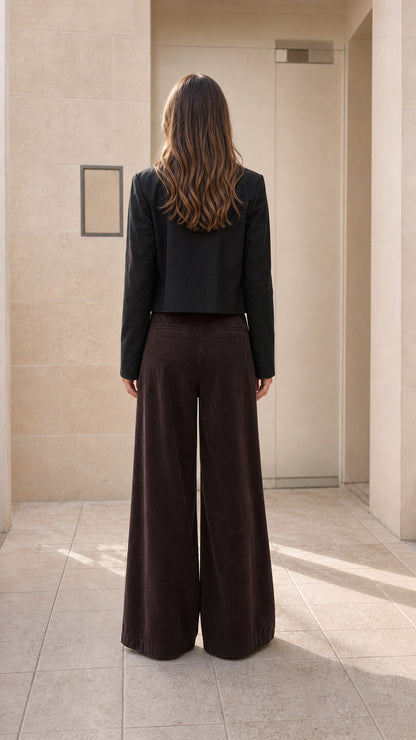 Back view of model wearing black cropped jacket with wide-leg trousers