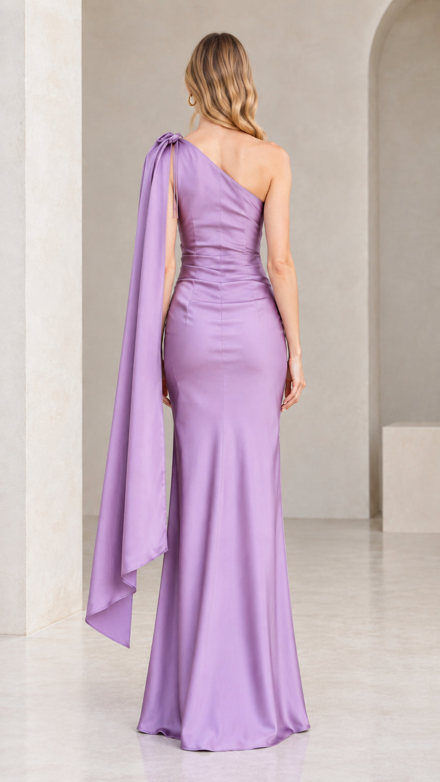 Back view of lavender one-shoulder evening gown highlighting the flowing capelet sash
