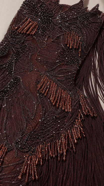 Close-up detail of intricate brown bead embroidery and fringe
