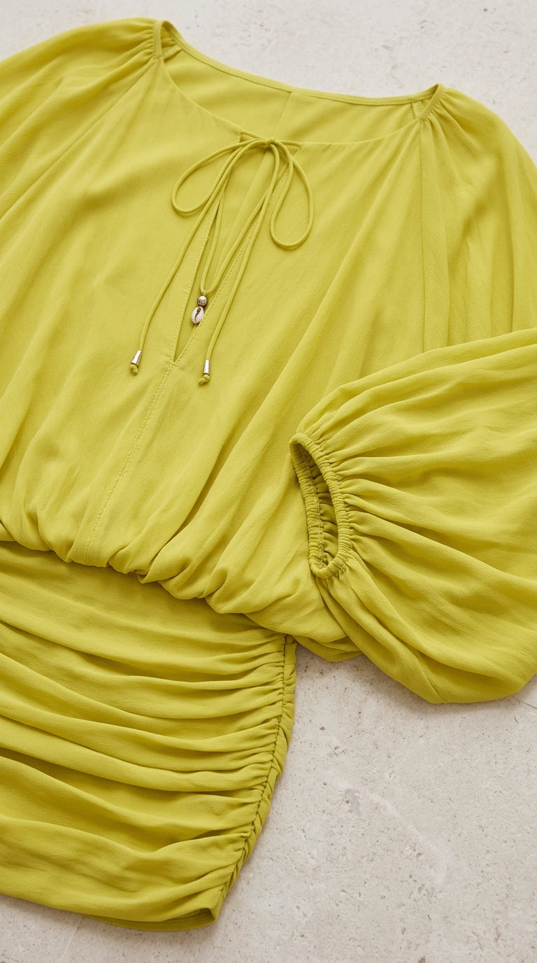 Close-up detail of tie-front neckline and ruched fabric on lime green dress