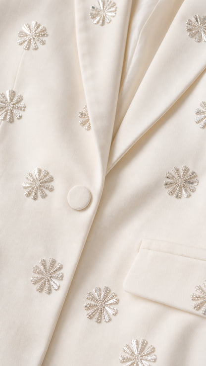 Close-up detail of rhinestone floral embellishments on cream blazer