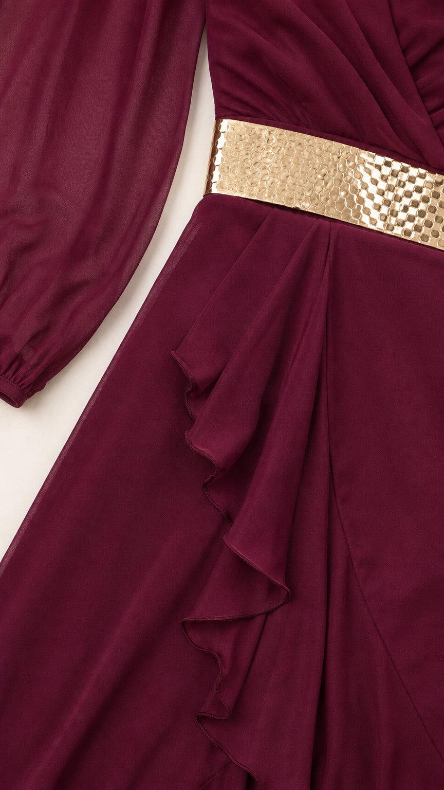 Close-up detail of burgundy chiffon fabric, gold metallic waist accent, and ruffle hem