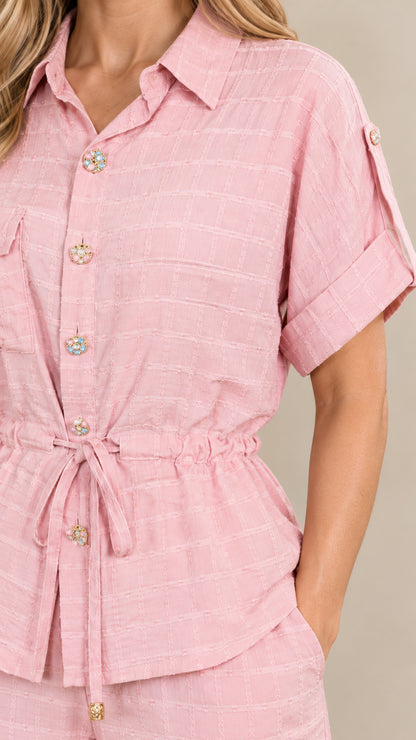 Close-up detail of soft pink textured fabric, buttons, and adjustable drawstring waist