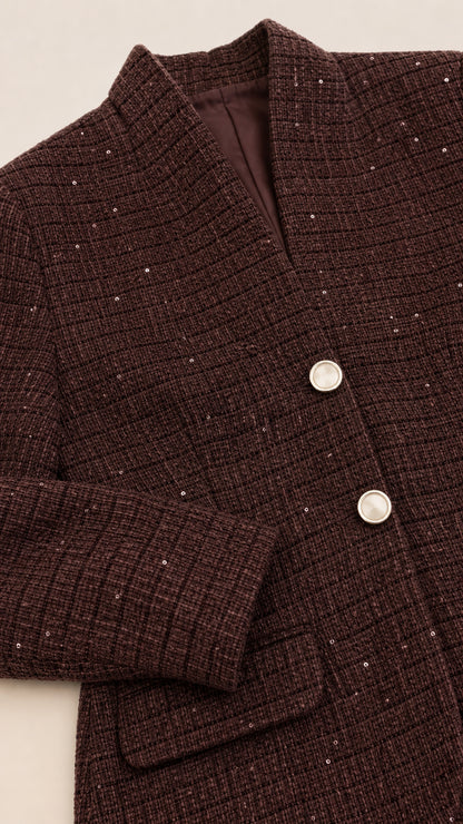 Close-up detail of chocolate brown tweed fabric with delicate shimmer accents and buttons