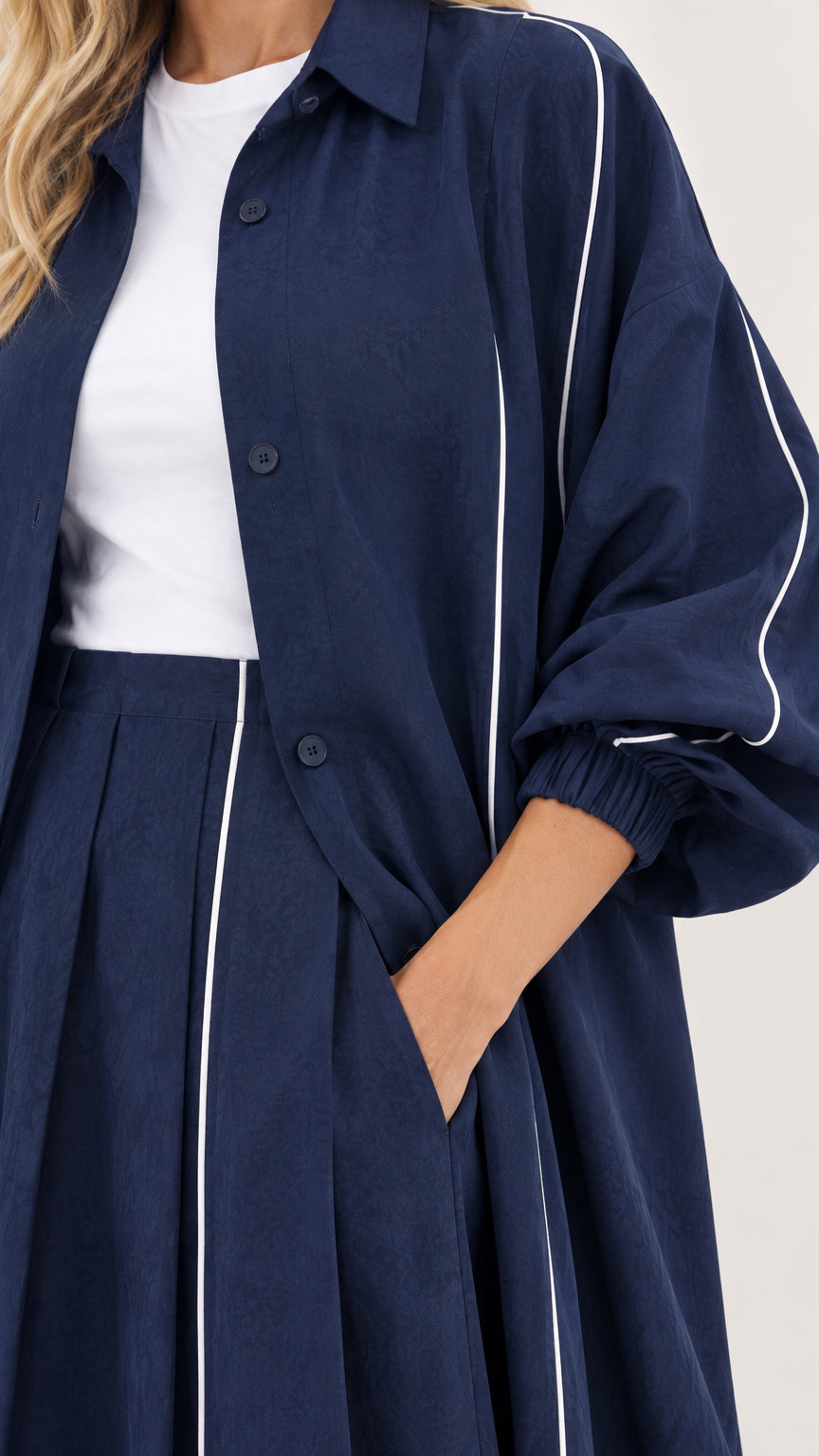 Close-up detail of navy duster collar, buttons, sleeve gathers, and white piping line