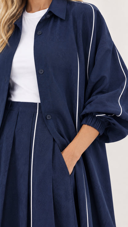 Close-up detail of navy duster collar, buttons, sleeve gathers, and white piping line