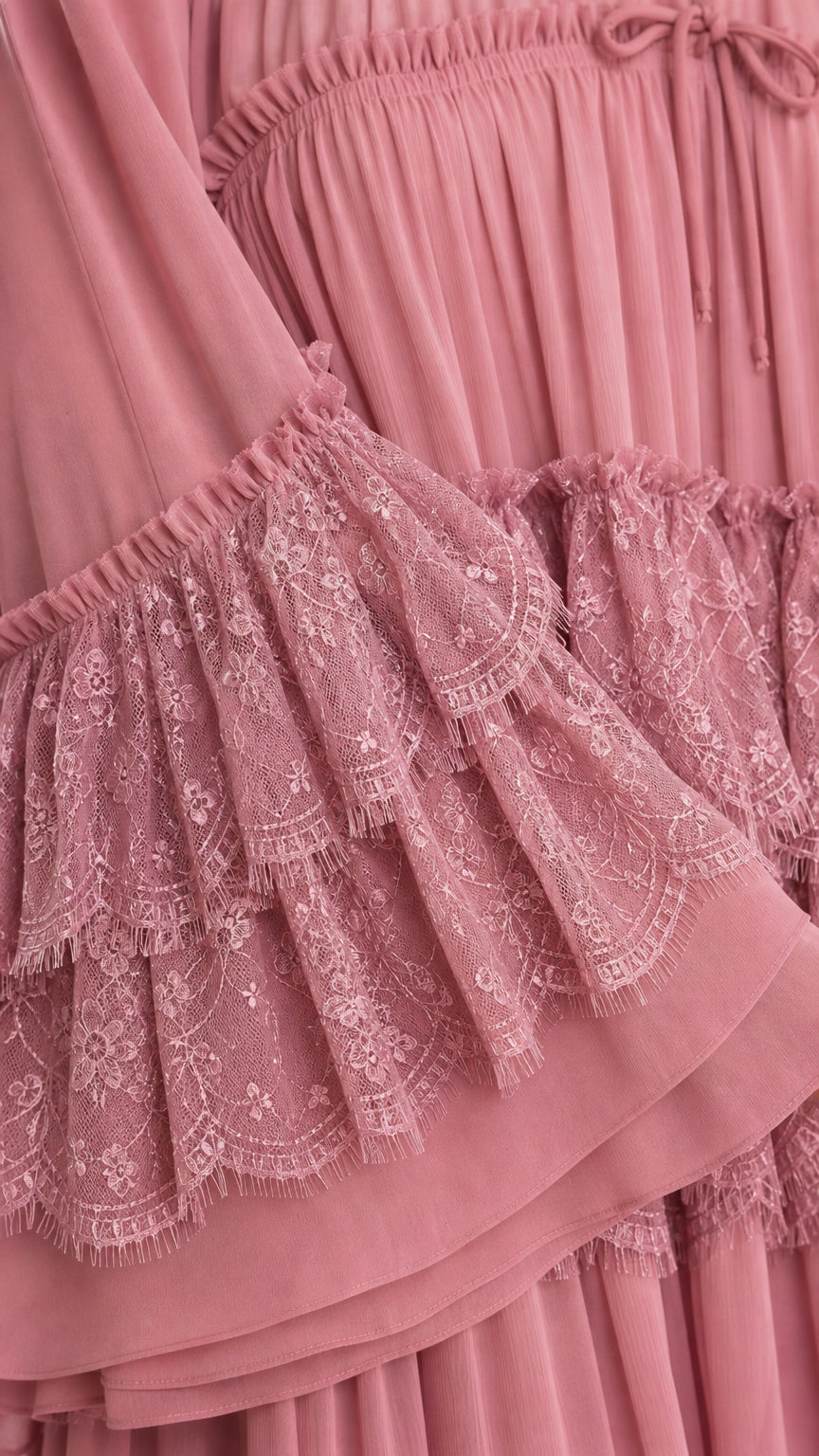 Close-up of delicate lace ruffles and pleated chiffon fabric in dusty rose