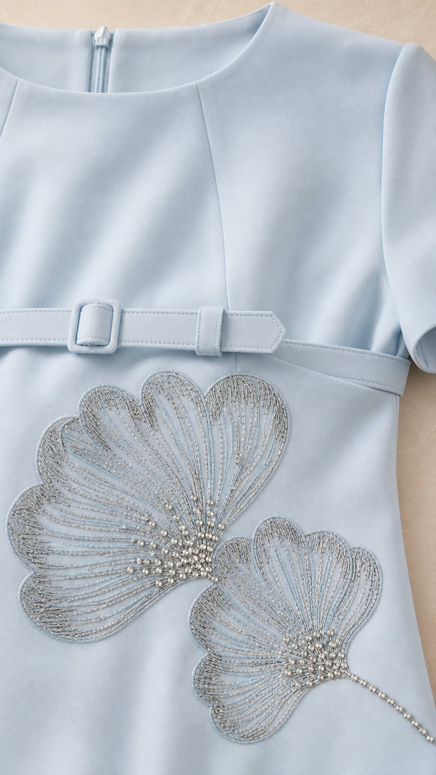 Close-up detail of Light Blue dress showing intricate beaded leaf embroidery and fabric belt