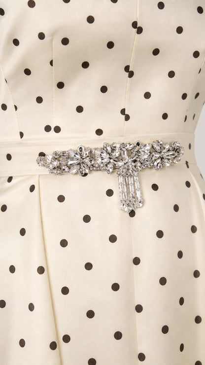 Close-up detail of rhinestone waist buckle and polka dot woven fabric