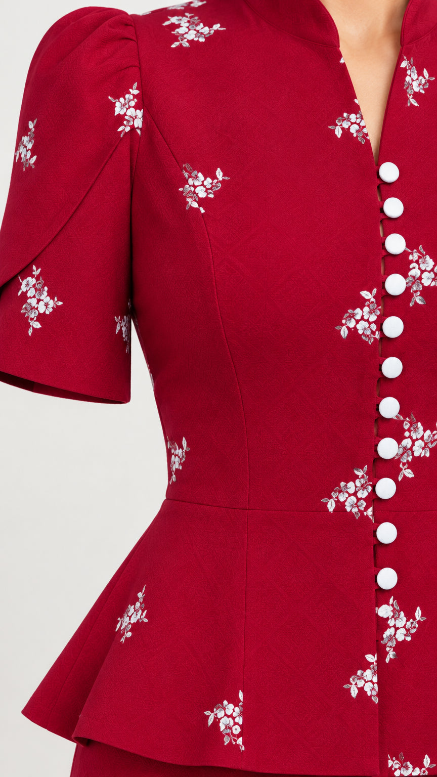 Close-up detail of white floral embroidery and button closure on burgundy peplum bodice