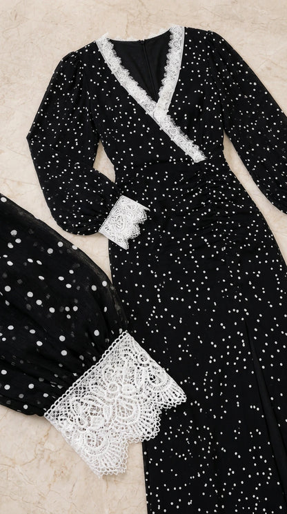 Close-up detail of white lace neckline and cuff trim on black polka dot dress
